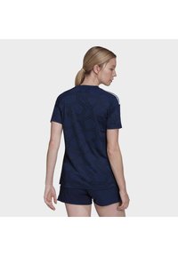 Maglietta sportiva navy con un motivo geometrico, maniche corte e colletto rotondo. Presenta strisce bianche sulle spalle e una vestibilità rilassata.