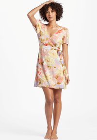Vestido wrap floral con mangas cortas abullonadas, escote en V y cinturón de lazo. Los colores incluyen rosa, amarillo y toques de verde y púrpura.