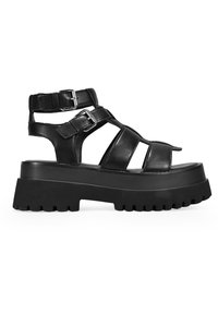 Sandalias de plataforma de cuero negro con múltiples correas, hebillas ajustables y una suela de goma gruesa y texturizada. Presentan elementos de diseño recortados.