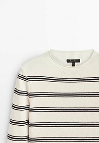 Biały sweter w czarne poziome paski, z prążkowanym dekoltem i mankietami. Miękka tekstura, lekki materiał, casualowy design. Widoczna metka.
