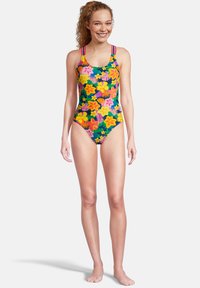 Maillot de bain une pièce avec une base bleu marine et des motifs floraux vibrants en rose, jaune et vert ; il dispose de larges bretelles et d'une coupe ajustée.