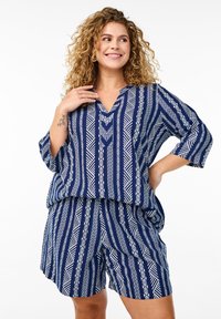 Conjunto informal en azul marino que incluye una blusa holgada y pantalones cortos a juego con patrones geométricos blancos, escote en forma de v y mangas de tres cuartos.