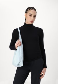 Must musta pikk käistega ribategija, tumedad kohandatud püksid ja helebeež pehme kott. Sujuv tekstuur ja minimalistlik disain.