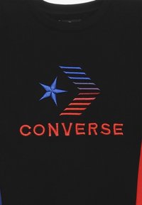 Felpa nera con logo "Converse" ricamato multicolore, con stelle e motivi a linee diagonali in blu, rosso e viola.