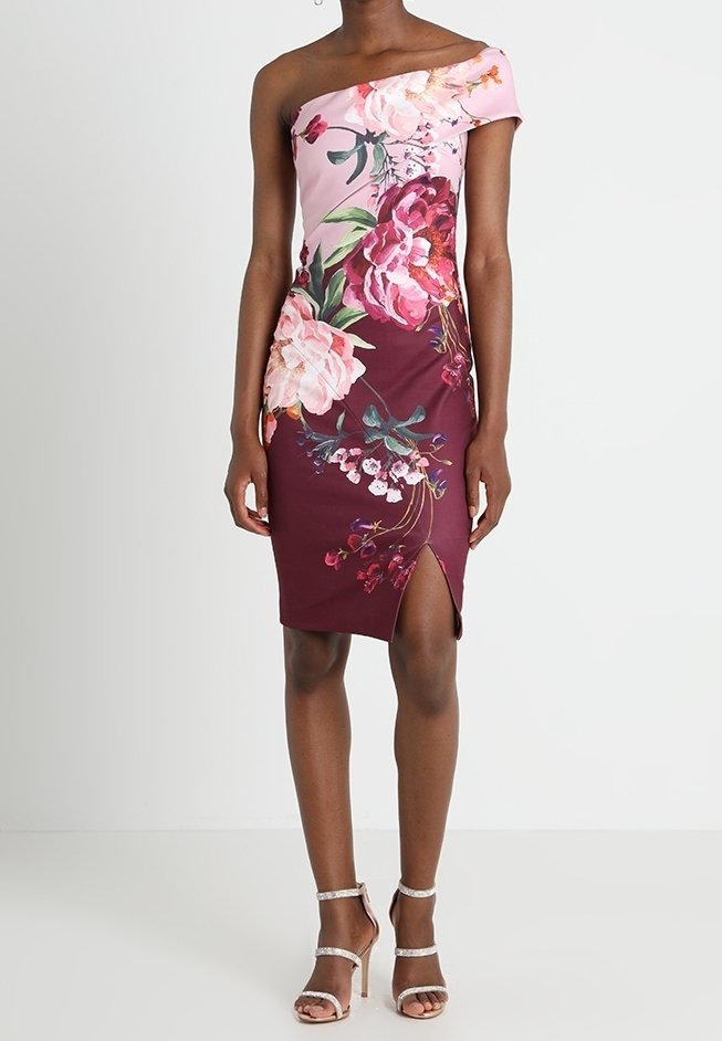 Robe florale décolletée, combinant des tissus rose et bordeaux, ornée de grands motifs floraux et d'une fente sur le côté, fabriquée en matière lisse.