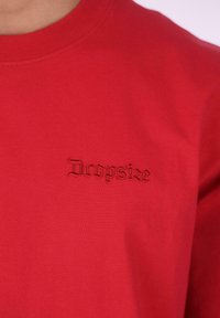 Rød bomulds T-shirt med rund halsudskæring og broderet "Dropsize" logo i mørkerød på brystet. Glat tekstur, casual design.