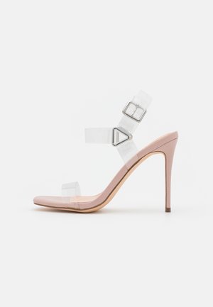 Pink stilet sandal med klare vinylremme og sølvspænde på hvid baggrund, vist fra siden.