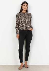 Bluzica dugih rukava s leopard uzorkom u bež i crnoj boji. Uparena s crnim uskim trapericama i sandalama u crnoj boji s leopard uzorkom.