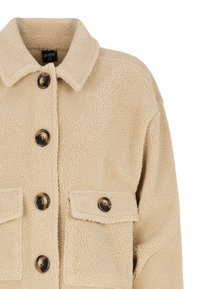 Beige fleecejakke med krave, frontknapper og to brystlommer. Strukturert stof med en blød og varm udseende.