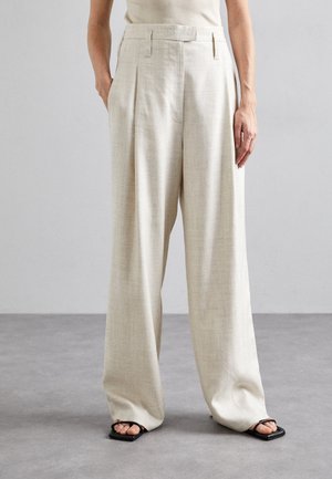 Pantalons taille haute beige clair avec plis, design à jambe large, tissu texturé et poches latérales. Assortis avec des sandales noires.