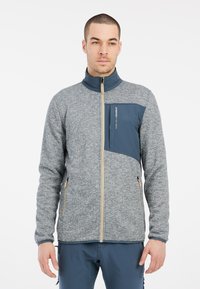 Grijze en marineblauwe fleecejas met een hoge kraag, textuurpatroon, rits aan de voorkant en borstzak. Voorzien van dubbele ritszakken aan de zijkanten.