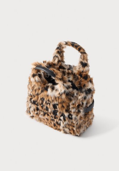 Petit sac à main avec texture en fausse fourrure léopard, anses courtes et une poche zippée noire sur le dessus, sur fond blanc.