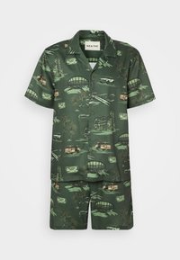 Kortærmet grøn skjorte og matchende shorts med et tropisk mønster med biler, palmer og vartegn i beige og gule nuancer.