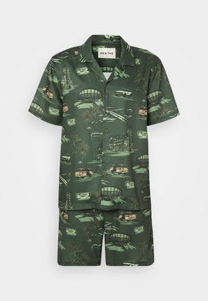 Koszulka z krótkim rękawem w zielonym kolorze i dopasowane szorty, z tropikalnym wzorem przedstawiającym samochody, palmy i zabytki w odcieniach beżu i żółci.