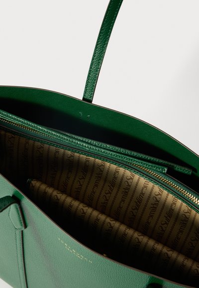 Grønt læder tote bag med en lynlåslomme foroven, struktureret beige indvendig foring trykt med "Sumika2S," og tynde skulderremme.