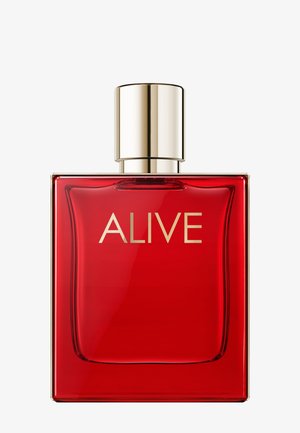 Czerwona prostokątna butelka perfum z złotą nakrętką i napisem "ALIVE" złotymi literami z przodu.