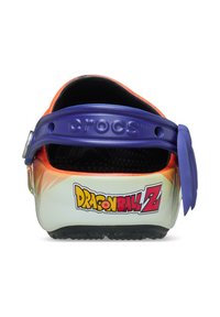 Crocs met een witte basis, oranje en paarse accenten, met een "Dragon Ball Z" logo op de hiel en een gestructureerd zwart interieur.