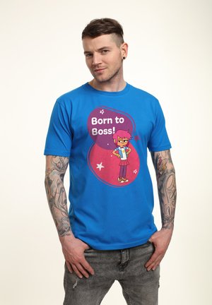 Blå bomulds t-shirt med et grafisk design, der har teksten "Født til at lede!" sammen med en karakterillustration i lyserøde og lilla nuancer.