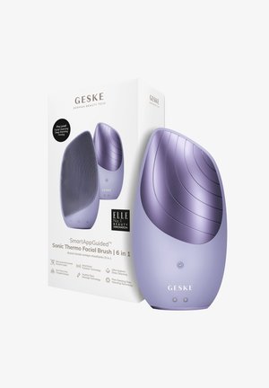Purple silicone sonic facial brush with textured cleansing surface and smooth curves. Packaged in a white box with product details displayed.