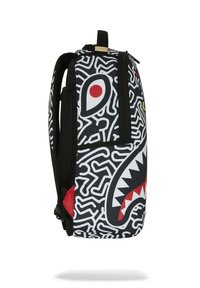 Mochila negra con patrón de laberinto blanco, diseño de boca de tiburón rojo y blanco, y un asa en la parte superior. Compartimentos con cremallera visibles en el lado.