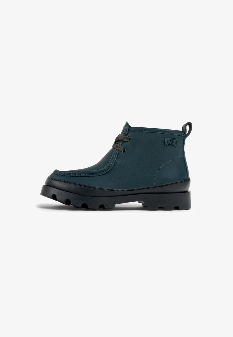 Bottine en cuir vert foncé à bout arrondi, avec des coutures contrastées, des lacets gris et une semelle en caoutchouc noir texturé et épais.