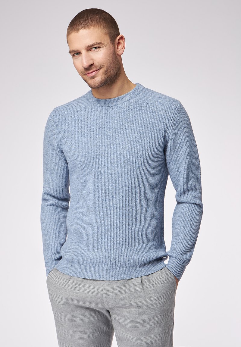 Maglione azzurro chiaro a coste con scollatura a girocollo e maniche lunghe, abbinato a pantaloni a quadri grigi. Tessuto morbido, design aderente.
