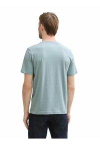 Hellblaues Baumwoll-T-Shirt mit Rundhalsausschnitt und kurzen Ärmeln, das über eine glatte Textur und eine lockere Passform verfügt, von hinten präsentiert.