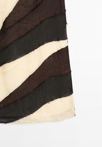 Stoff mit welligen, abwechselnd dunkelbraunen, schwarzen und beigen Streifen, mit rohen Kanten und leicht transparenter Textur.