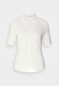 Blouse blanche à manches courtes avec boutons, col, taille cintrée et tissu lisse, présentée sur un fond gris clair uni.