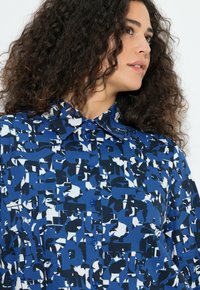 Blauw overhemd met knopen, voorzien van een gedurfd, abstract patroon in marineblauw en wit. Gemaakt van lichtgewicht stof met een klassieke kraag en een gestructureerde afwerking.