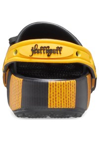 Schwarze und gelbe Clogs mit strukturiertem Design, einem strukturierten Fußbett und "Hufflepuff"-Branding am Riemen, ergänzt durch kontrastierende seitliche Akzente.
