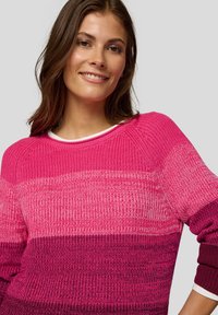 Gestrickter Pullover mit einem Farbverlauf in Rosatönen. Gerippte Struktur, U-Boot-Ausschnitt und kontrastierende weiße Umrandung am Kragen.