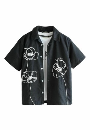 Zwart kortärmlig overhemd met knopen met witte abstracte bloemlijntekeningen en de tekst "BAKER" op de rechterborst over een wit grafisch T-shirt.