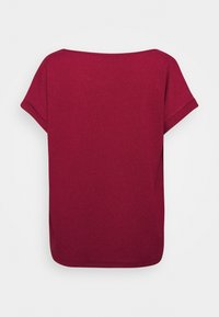 Top rouge à manches courtes avec une coupe décontractée, un col rond et un tissu texturé. Design du dos sans coutures, sans fermetures éclair ni embellissements visibles.