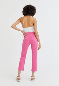 Jean en denim rose taille haute avec une jambe droite, cinq poches et une finition soignée. Le tissu a une texture lisse.