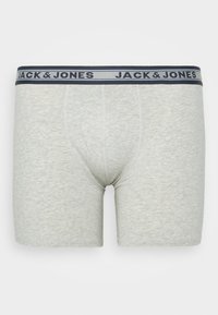 Graue Baumwoll-Boxershorts mit einem marineblauen Elastikbund, auf dem der Markenname "JACK & JONES" in weißer Schrift steht. Glatte Textur, taillierte Passform.