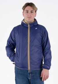 Giacca leggera blu navy con cappuccio, chiusura a zip completa e polsini elasticizzati. Presenta una cerniera gialla a contrasto e un logo sul petto.