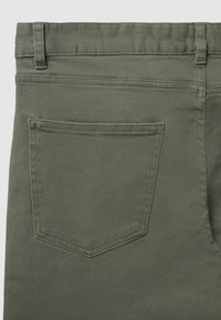 Pantalons en denim vert olive vus de l'arrière, avec une poche rectangulaire simple ornée de coutures discrètes.