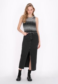 Schwarzer Denim-Maxi-Rock mit vorderem Schlitz, kombiniert mit einem ärmellosen metallisch schimmernden Top mit Ombre-Effekt, das ein strukturiertes Muster und Perlenakzente aufweist.