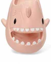 Zapato de goma rosa diseñado como una cara de dibujos animados con grandes dientes blancos y ojos negros; presenta una forma redondeada y una textura suave.