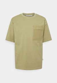 Olivově zelené tričko s krátkým rukávem z měkké bavlny, s kapsou na hrudi a kulatým výstřihem. Čisté linie s minimalistickým designem.