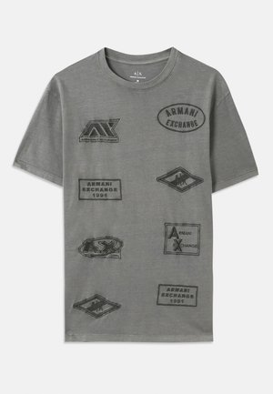 Camiseta de algodón gris con múltiples parches en relieve que presentan la marca "Armani Exchange" en varias formas y tamaños. Diseño de cuello redondo.