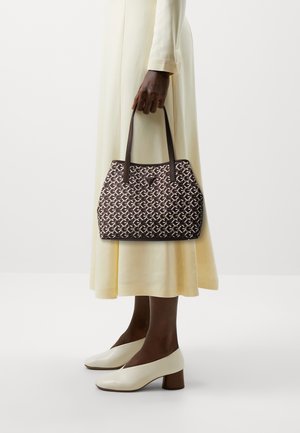 Sac à main marron à motifs avec deux poignées, forme structurée et accents en cuir, associé à une robe fluide jaune clair et des talons beiges.