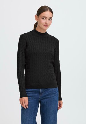Black cable-knit sweater with long sleeves and a high neck, featuring a textured pattern. Worn with blue denim jeans.