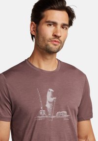 Camiseta de manga corta color granate, hecha de una tela suave, con un gráfico de un oso blanco que sostiene un remo, equipo de pesca y un objeto redondo debajo.