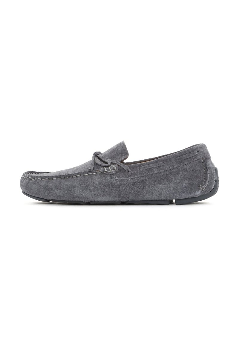 Zapato de ante gris estilo mocasín con un perfil bajo, puntera redondeada, costuras decorativas y una suela de goma delgada. Sin herrajes visibles.