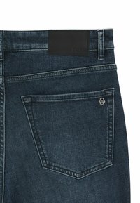 Mørkeblå denim jeans med en glat tekstur. Har en sort læderpatch mærket "BOSS" i taljen og et lille logo på baglommen.