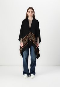 Poncho nero con accento a stampa leopardata sull'orlo, realizzato in tessuto morbido. Il design presenta un bordo frangiato e una silhouette drappeggiata.