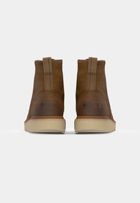 Bottes de cheville en cuir marron avec un talon rigide, une tige texturée et une semelle en caoutchouc crème avec un logo subtil à l'arrière.