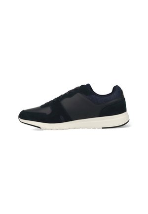 Baskets de sport bleu marine avec une tige en cuir lisse et en daim, semelle intermédiaire blanche contrastante et accent texturé au talon. Design à lacets.
